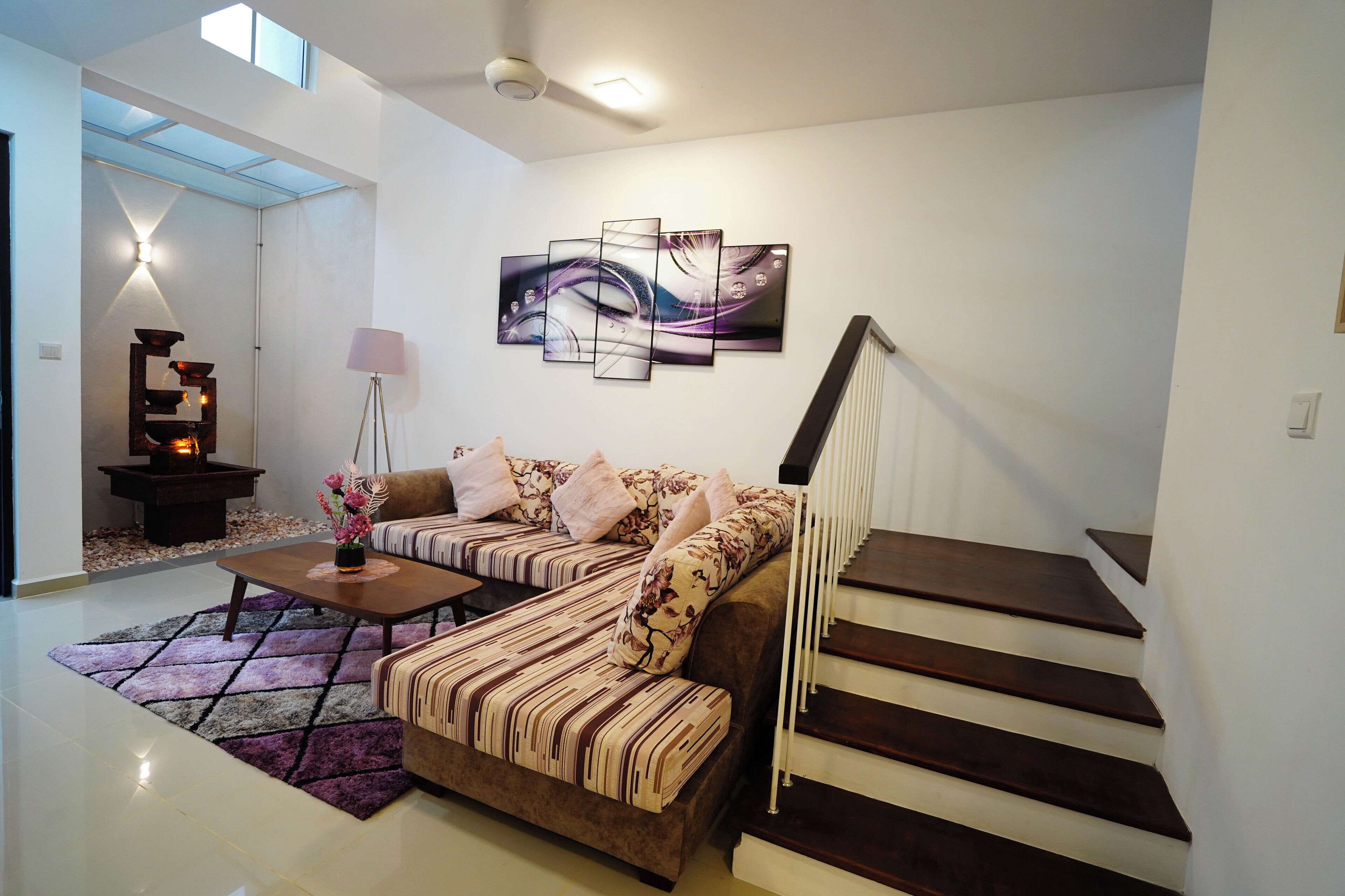 A modern living room with a sofa, coffee table, and a staircase.