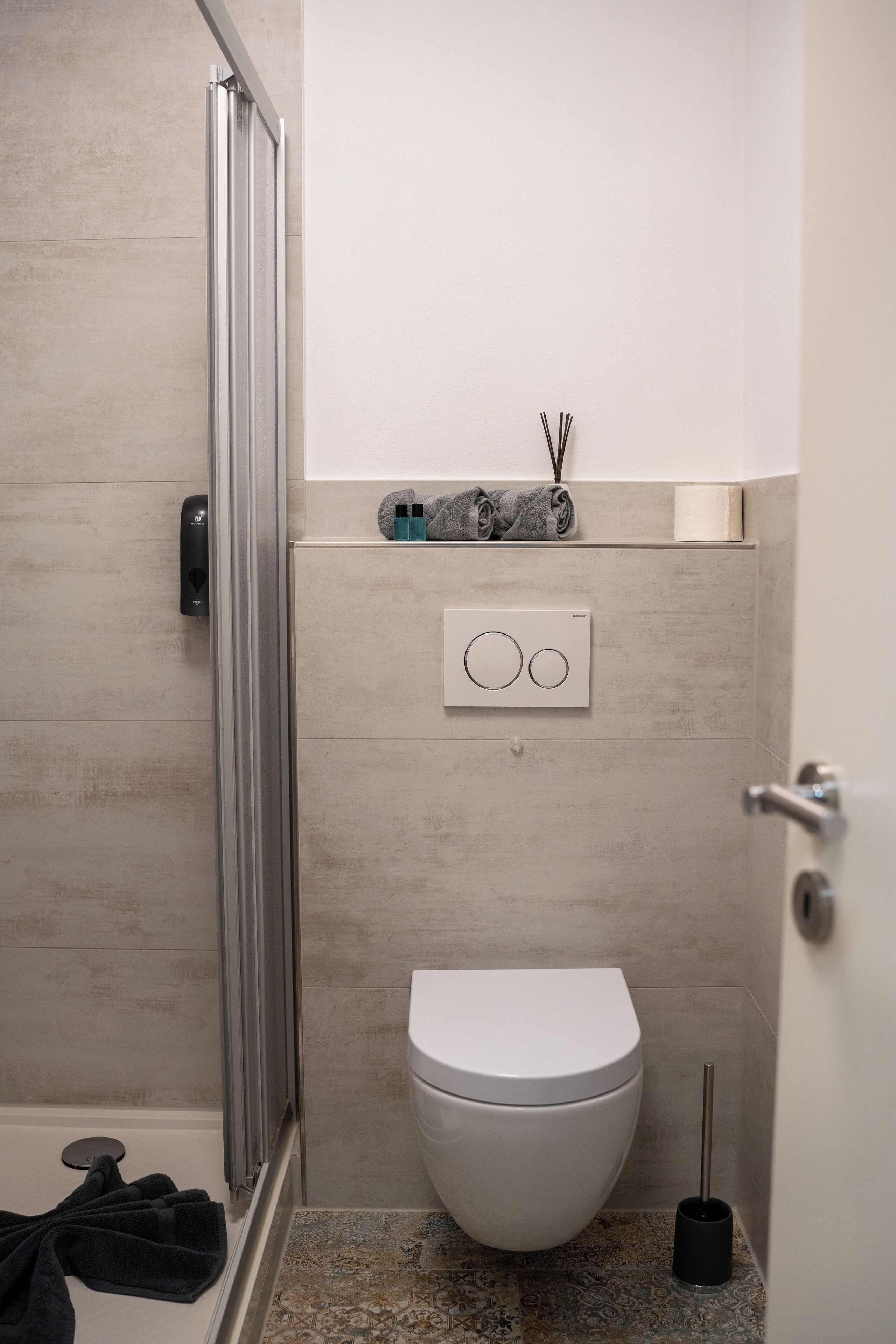 A modern bathroom with a shower, toilet, and a towel rack.