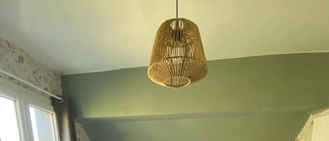 Une chambre à coucher avec un grand lit, un luminaire suspendu, une fenêtre et une porte.