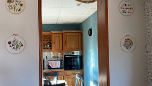 Une cuisine avec des meubles de rangement en bois, une table à manger avec des chaises et un luminaire suspendu.