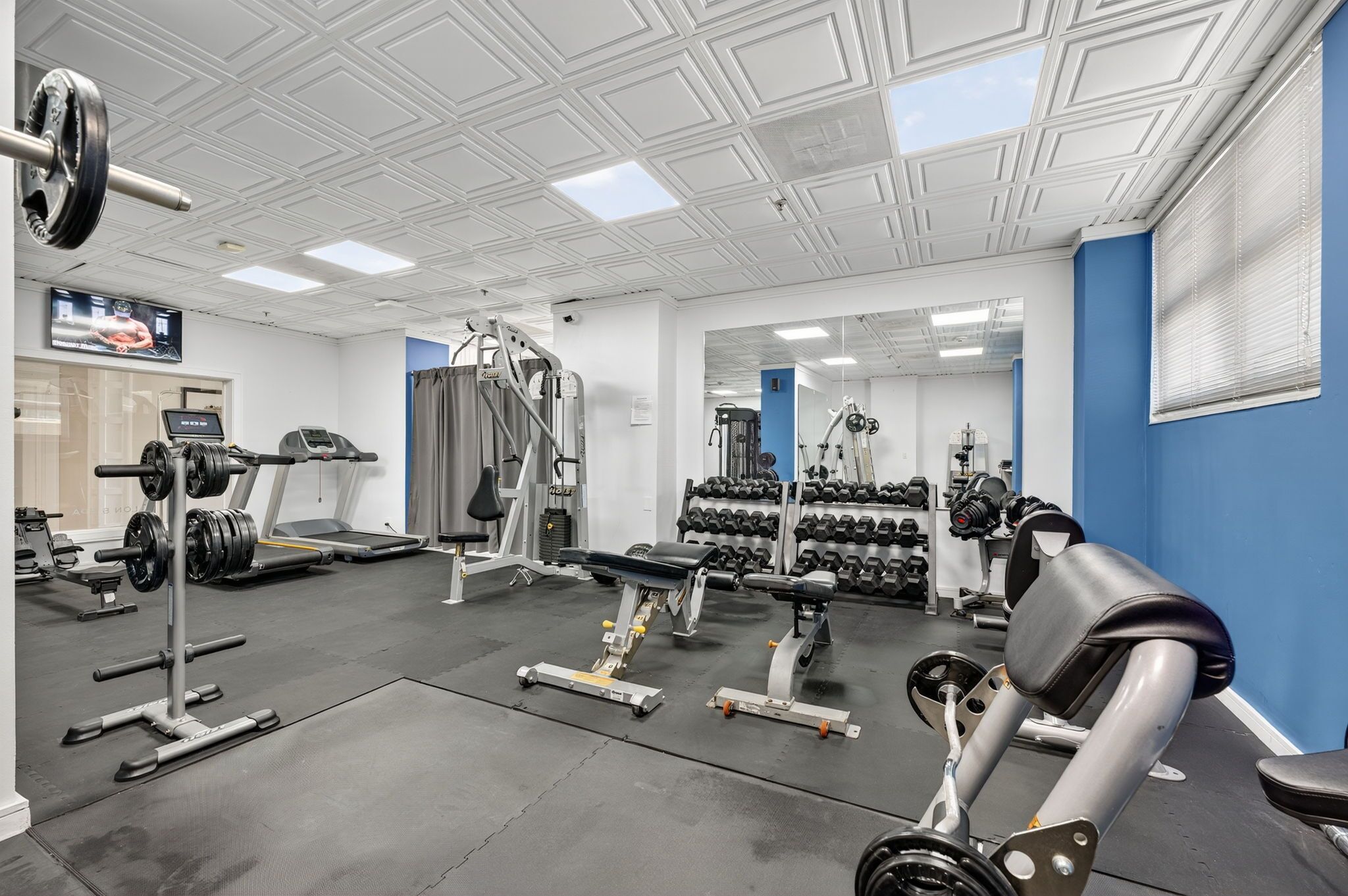 Ein Fitnessstudio mit Kraftgeräten, Laufbändern und Kurzhanteln.
