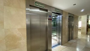 Two elevator doors labeled 'ASCENSOR' in a modern building with a tiled floor.