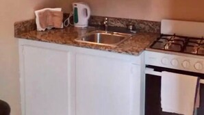 A compact kitchen with white cabinets, a microwave, a kettle, and a gas stove. - La Casa Duncy's Studio Apartment Getaway (Yambou River)