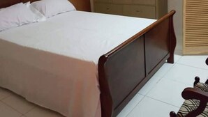 A bedroom with a wooden bed, a dresser, a mirror, and a clock on the wall. - La Casa Duncy's Studio Apartment Getaway (Yambou River)