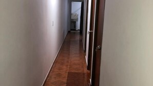 En lång, smal hall med kakelgolv och vita väggar.