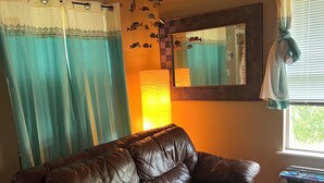 Un canapé en cuir marron dans une pièce dotée d’un plafond en bois, d’un miroir et d’une fenêtre avec des rideaux.