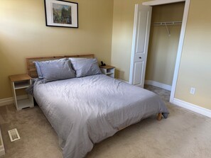 A bedroom with a bed, nightstands, a closet, and a picture on the wall.