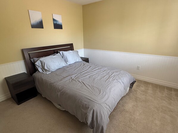 A bedroom with a bed, nightstands, and two wall-mounted pictures.