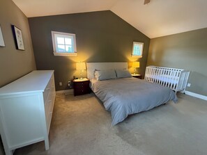 A bedroom with a bed, nightstands, a crib, and two windows. - Spacious 4BR retreat in South Surrey/ White Rock (Surrey)