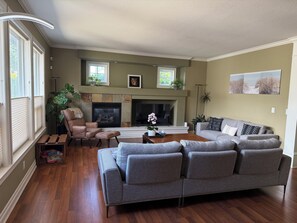 A living room with a fireplace, sofas, and a coffee table. - Spacious 4BR retreat in South Surrey/ White Rock (Surrey)