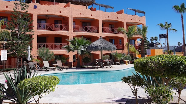 Un hotel amb múltiples balcons, una piscina i palmeres.