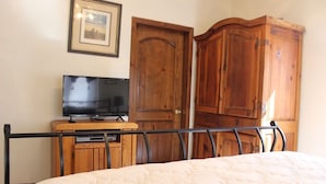 Ein Schlafzimmer mit einem Bett, einem Fernseher auf einer Holzkommode und Holzschränken.