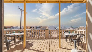 A wooden deck with tables and chairs, overlooking a beach and buildings. - Cypress House Close Distance to the Beach at Las Conchas (Puerto Peñasco)