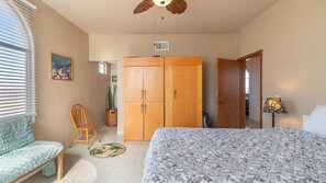 A bedroom with a bed, a wooden wardrobe, a chair, a lamp, and a window with blinds. - Cypress House Close Distance to the Beach at Las Conchas (Puerto Peñasco)