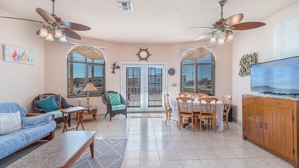 A living room with a sofa, chairs, a dining table, ceiling fans, and a TV. - Cypress House Close Distance to the Beach at Las Conchas (Puerto Peñasco)