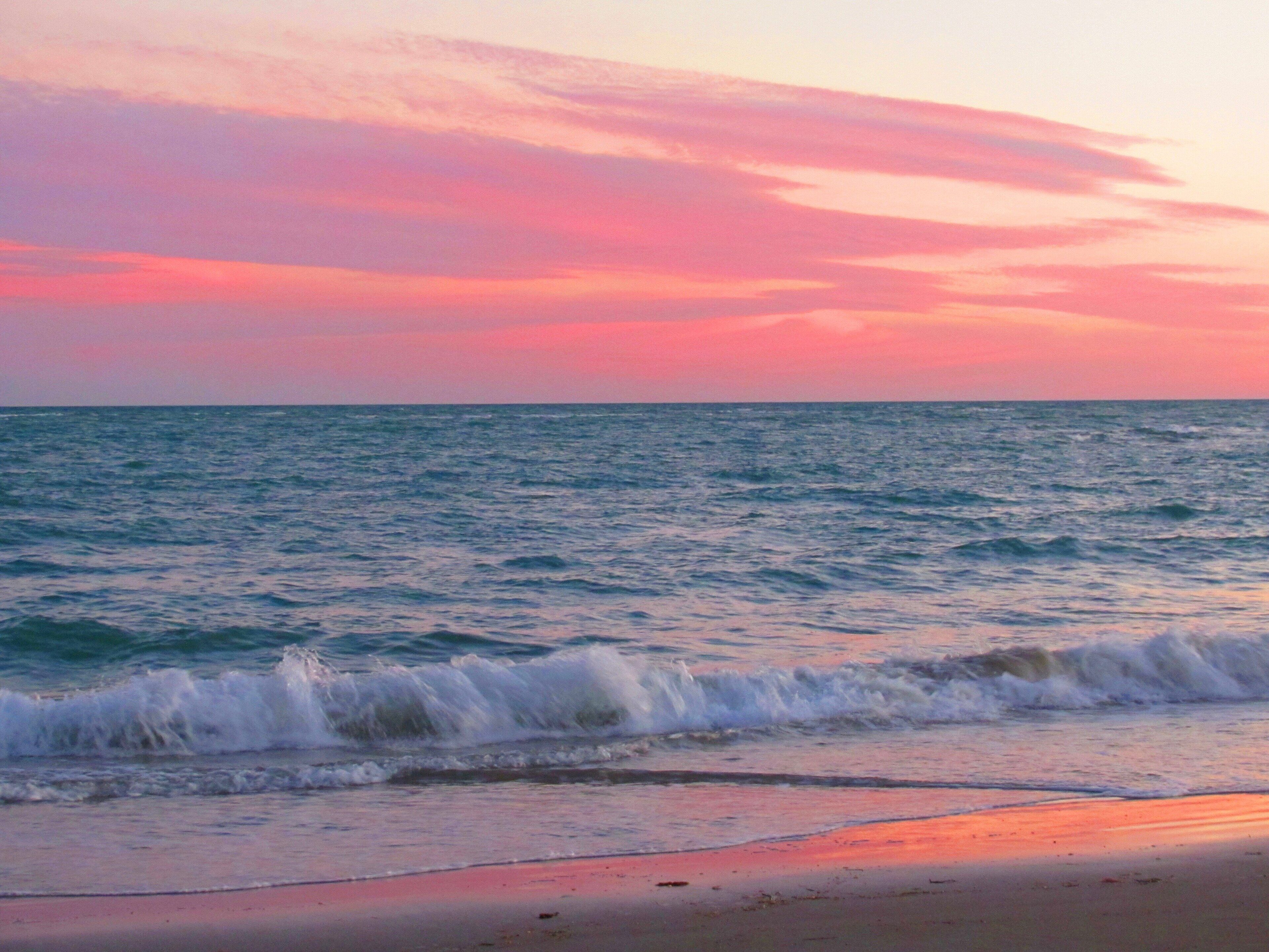 A beach with waves and a sunset.