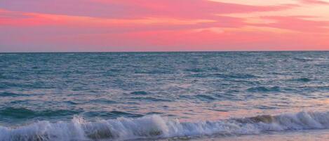 A beach with waves and a sunset.
