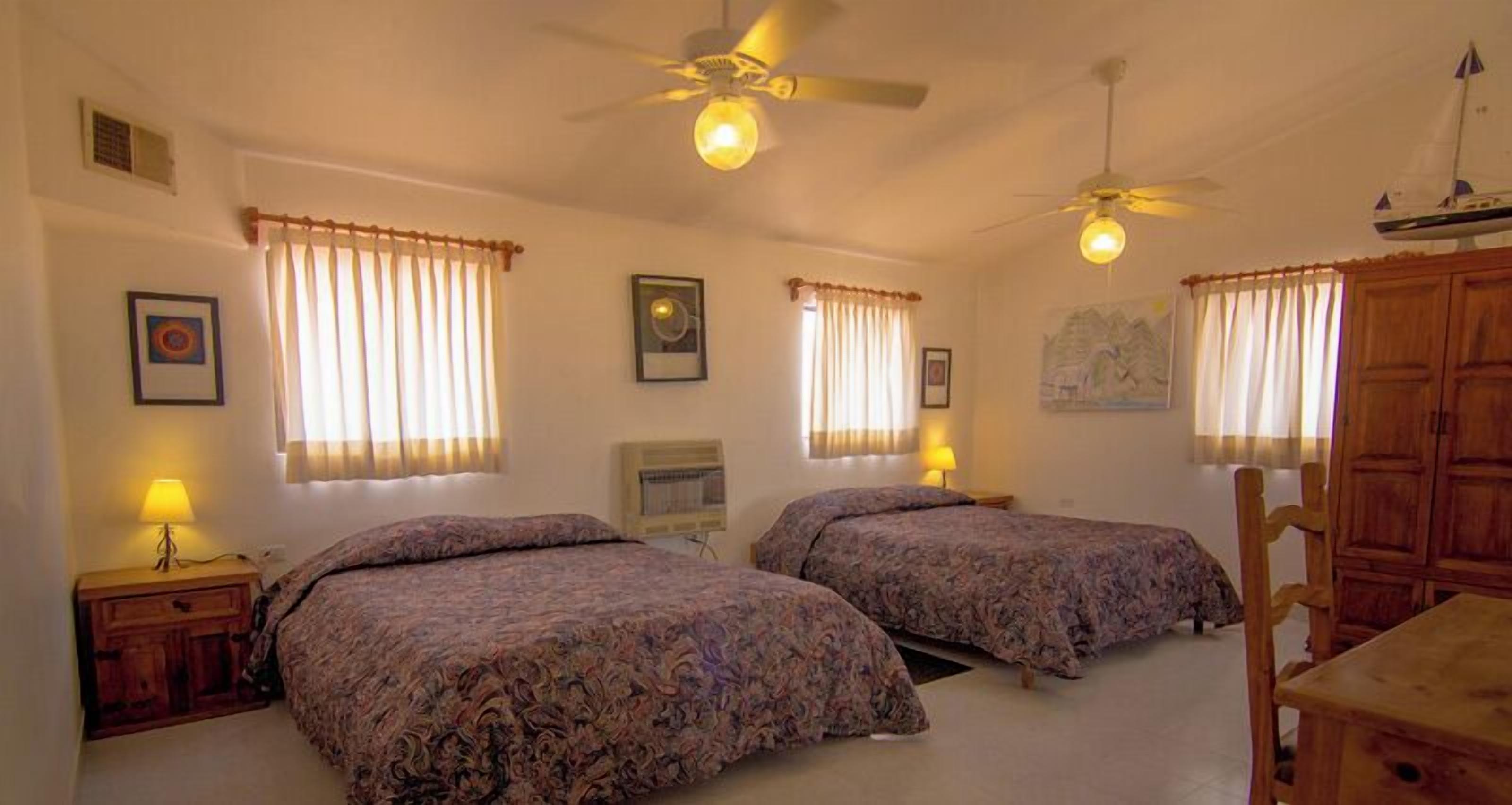 A bedroom with two beds, a ceiling fan, and a desk with a chair.