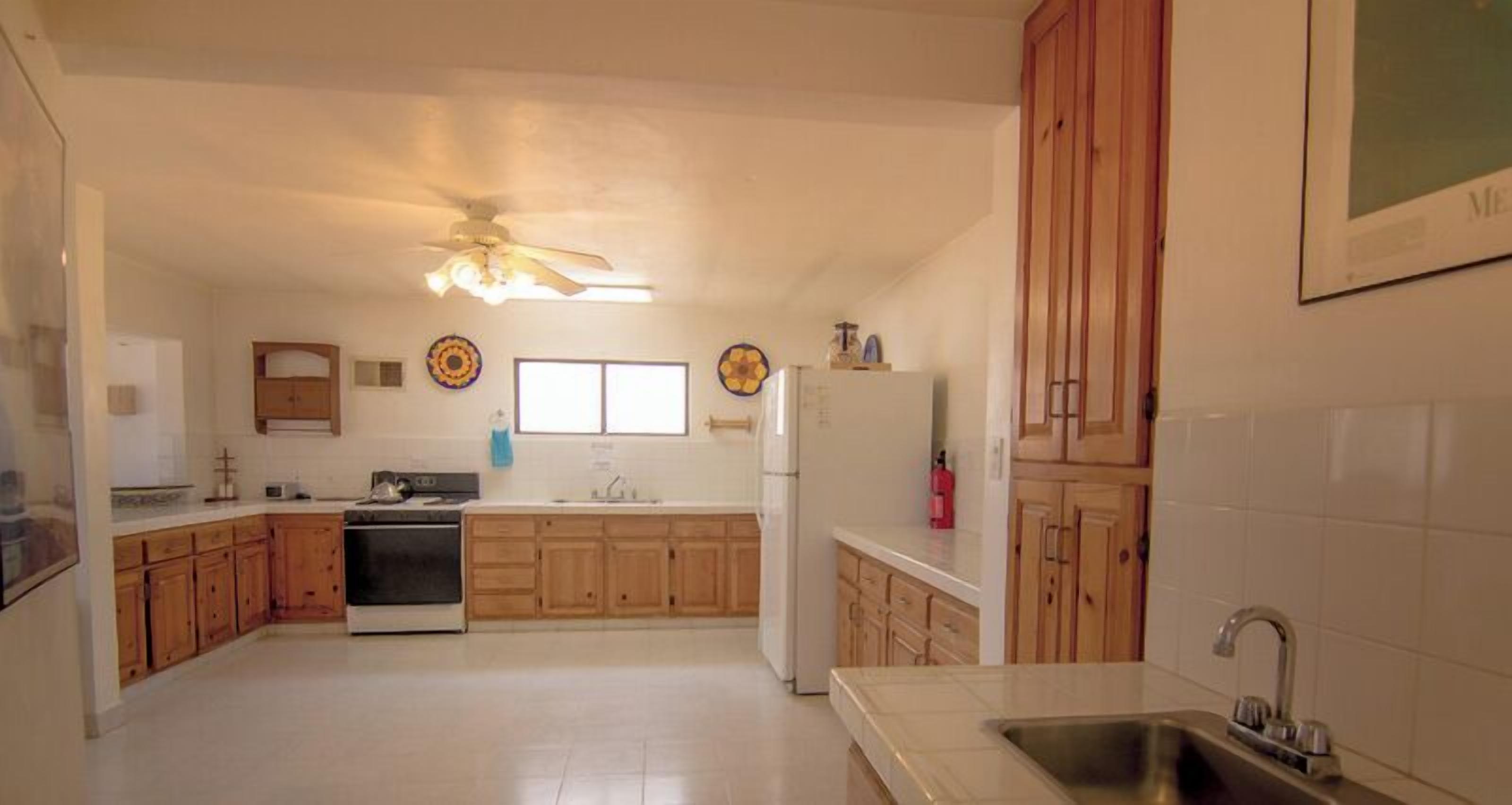 A kitchen with wooden cabinets, a stove, a refrigerator, and a ceiling fan.