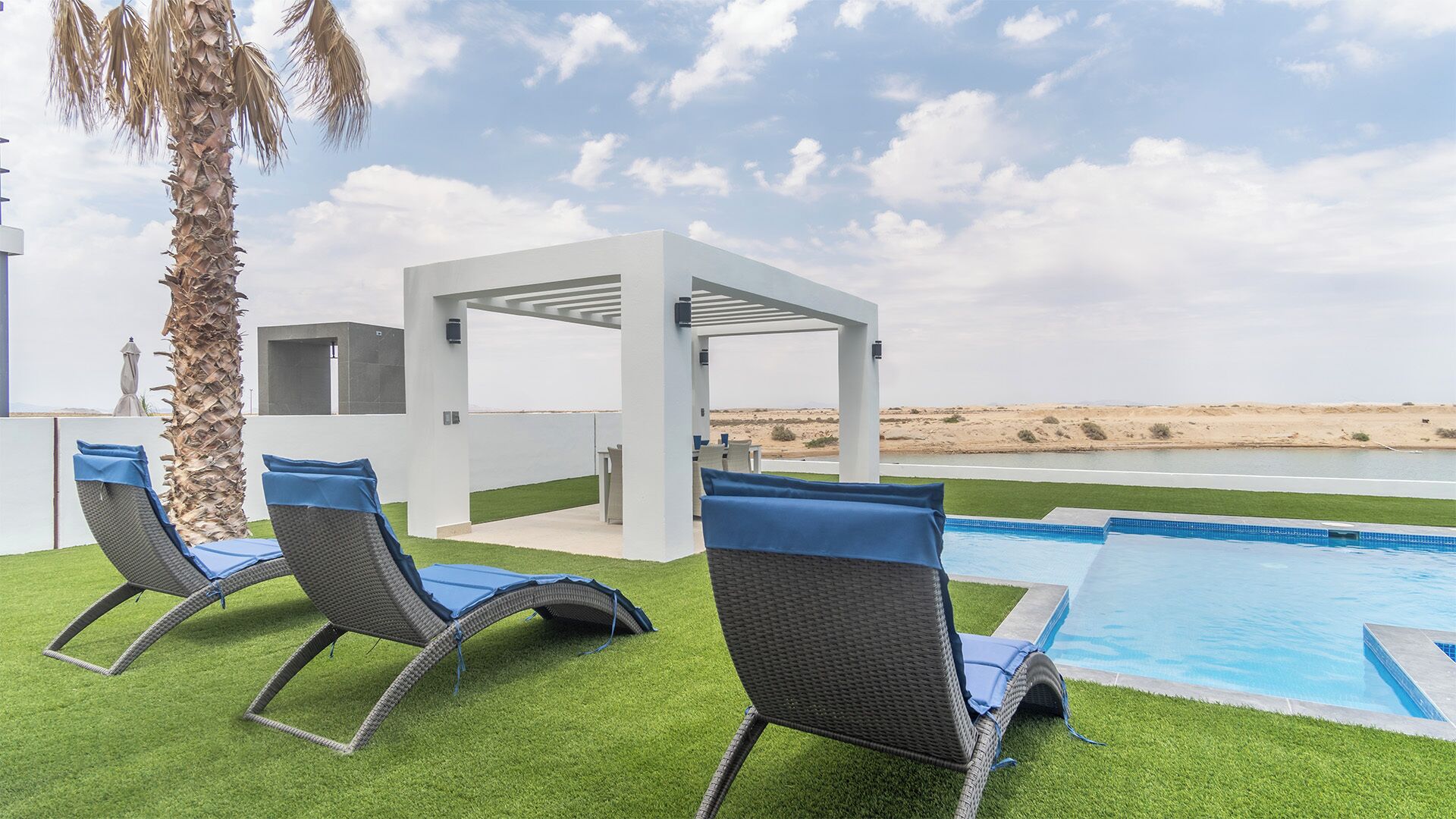 Ein Poolbereich mit Liegestühlen und einer Pergola mit Blick auf eine Wüstenlandschaft.
