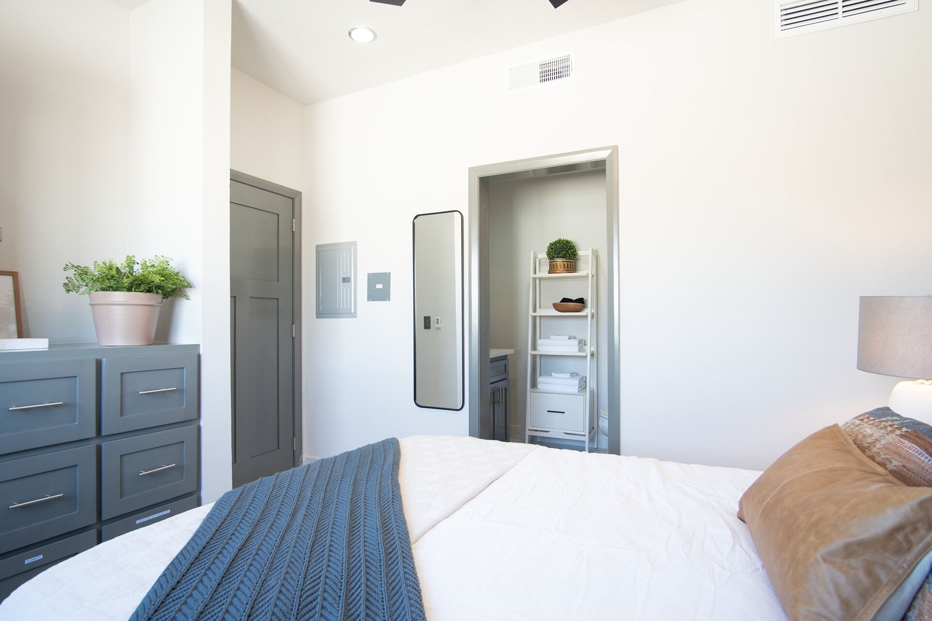 Un dormitorio con cama, cómoda, espejo, armario y planta en maceta.