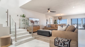 A spacious living area with a modern staircase, a comfortable sofa set, and a large TV screen. - 4 BR Luxurious Oceanfront Casa Estrella in Islas del Mar (Puerto Peñasco)