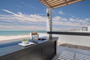 Un área de bar moderna al aire libre con vistas a la playa y al océano.