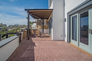 Un patio con pérgola, mobiliario exterior y vista a la playa.