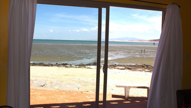 A room with a large sliding glass door leading to a beach view. - Casa Arco Iris Brand New 2-story Spacious Home Cholla Bay Ocean Front (Puerto Peñasco)