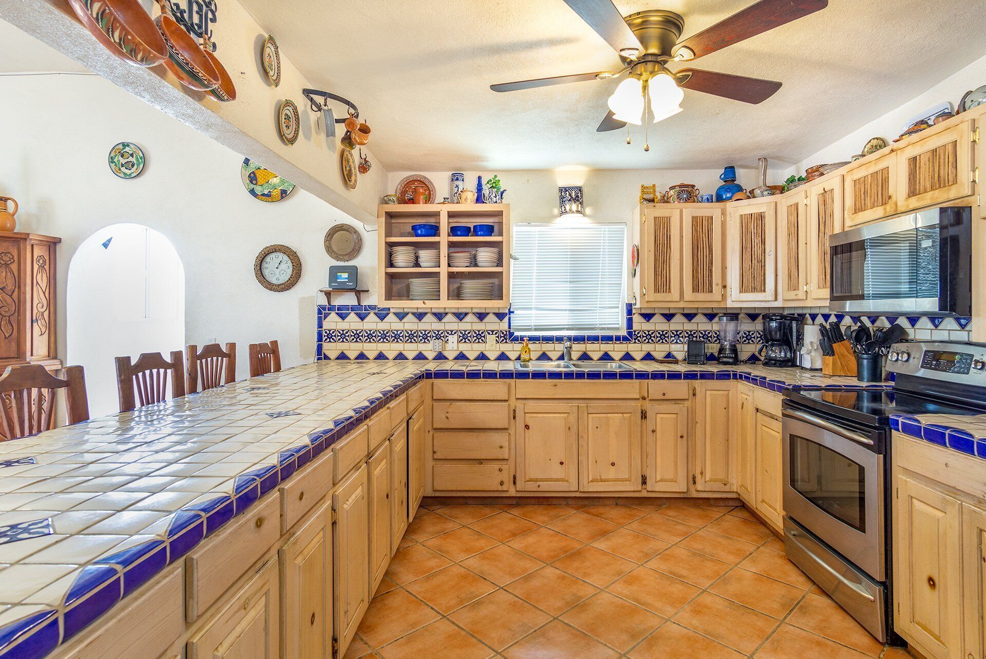 A kitchen with wooden cabinets, a tiled backsplash, and a large island with a sink.