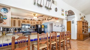 Une cuisine avec des meubles en bois, un pare-feu en carrelage et un îlot central doté de tabourets de bar.