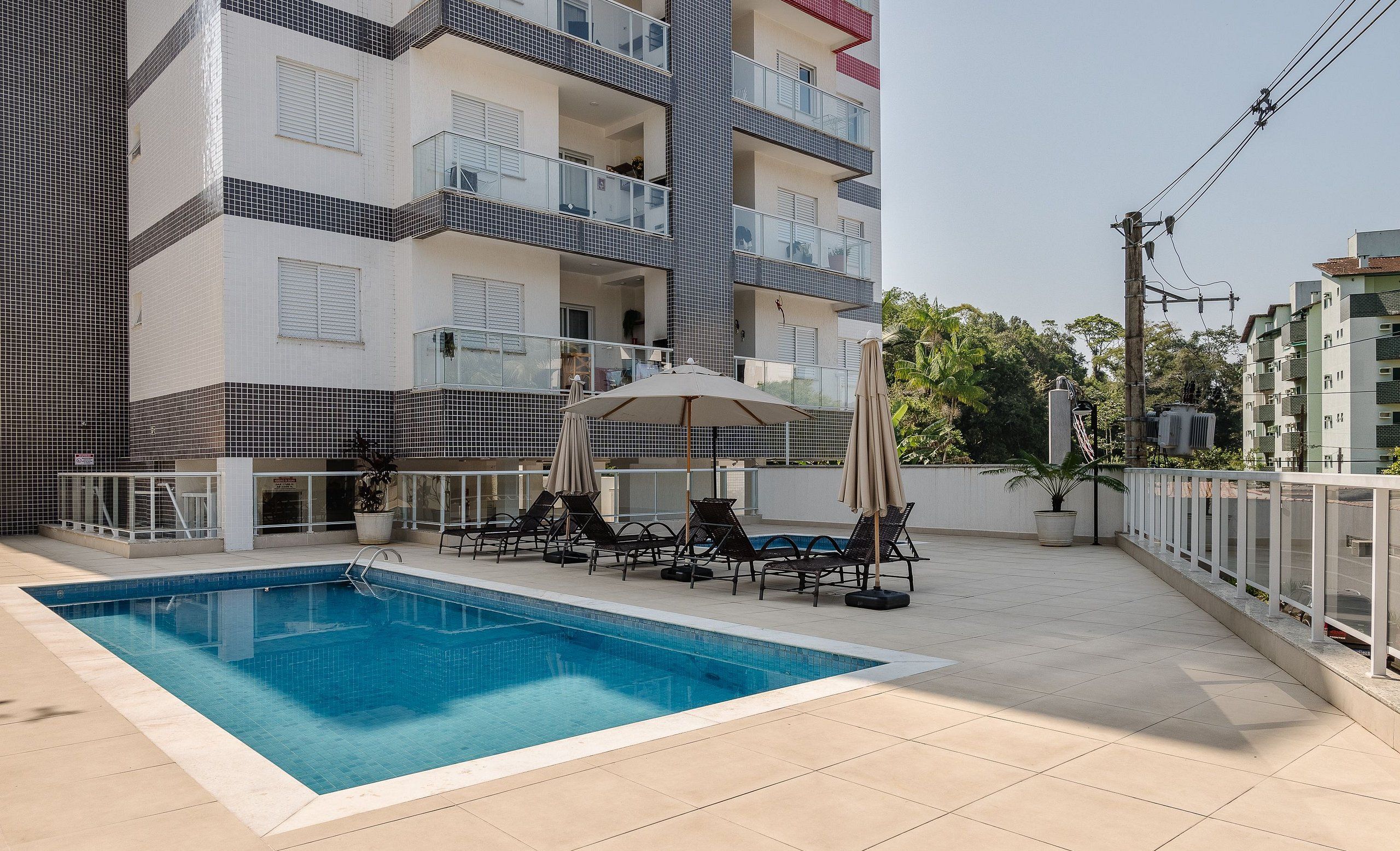 Une piscine entourée d’une terrasse carrelée, agrémentée de chaises longues et de parasols.