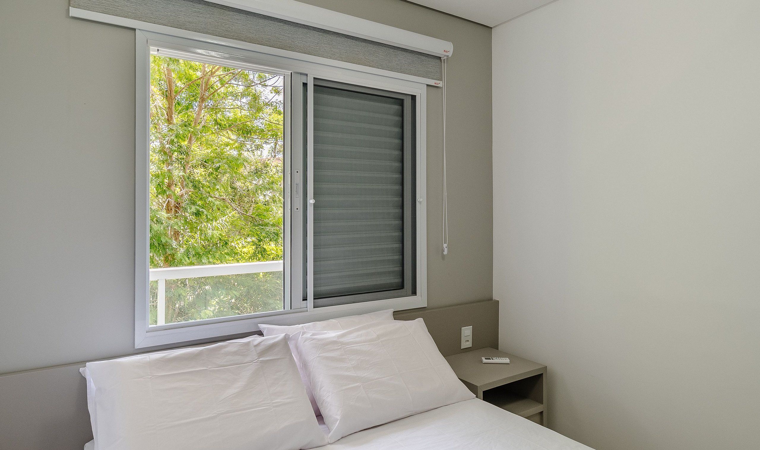 Un dormitorio con cama, mesita de noche y ventana con persianas.