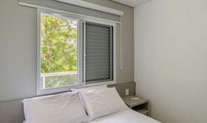 A bedroom with a bed, a nightstand, and a window with blinds. - Comfort and Leisure 500m From the Beach - Ire0022 (Ubatuba)