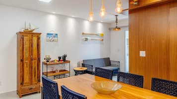 Un comedor con una mesa de madera, sillas azules y un modelo de barco en la pared.