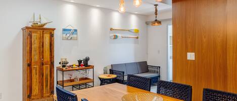 Un comedor con una mesa de madera, sillas azules y un modelo de barco en la pared.