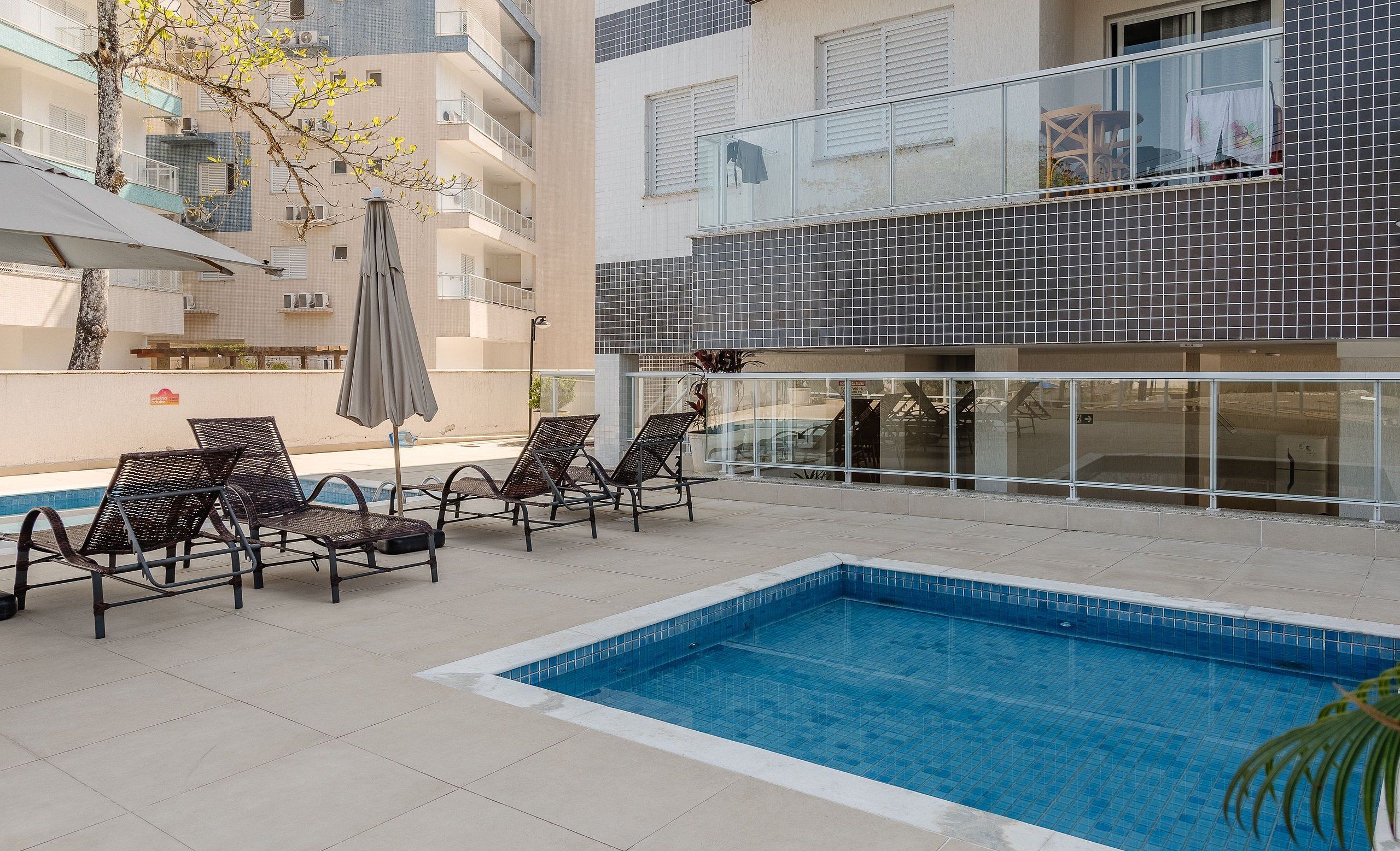 Un área de piscina en la azotea con sillas de descanso y una piscina.