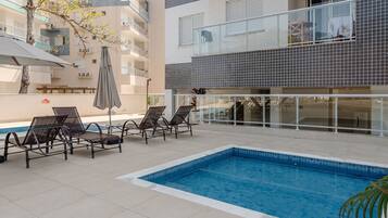Un área de piscina en la azotea con sillas de descanso y una piscina.