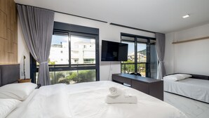 A modern hotel room with two beds, a desk, a flat-screen TV, and large windows offering a city view. - High Standard Studio on the Sand in Floripa Irb205 (Florianópolis)