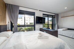 Une chambre d’hôtel moderne dotée de deux lits, d’un bureau, d’une télévision à écran plat et de grandes fenêtres offrant une vue sur la ville.