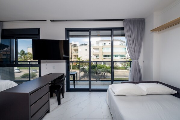Una habitación de hotel moderna con un ventanal grande, un escritorio, una cama y un televisor.