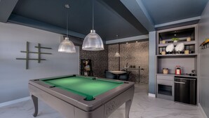A modern pool table in a room with a marble floor, pendant lighting, and a built-in bar area with shelves and a refrigerator. - High Standard Studio on the Sand in Floripa Irb205 (Florianópolis)