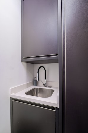Eine moderne Küche mit Spüle aus Edelstahl, einem schwarzen Wasserhahn und einer weißen Arbeitsplatte.