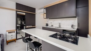 A modern kitchen with a central island, dark cabinets, and a white countertop. - High Standard Studio on the Sand in Floripa Irb205 (Florianópolis)