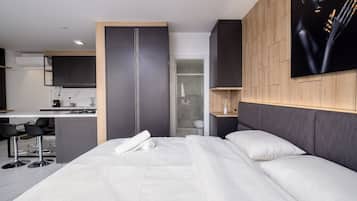 Une chambre d’hôtel moderne équipée d’un lit, d’un bureau et d’une kitchenette.