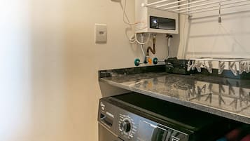 Un área de lavandería compacta con lavadora de carga frontal, secadora y panel de control.