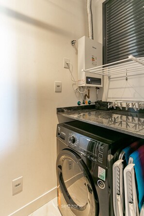 Een kleine wasruimte met een voorlader wasmachine, een droger en een bedieningspaneel.