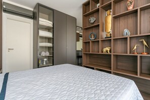 Une chambre à coucher comprenant un lit, une armoire et une étagère en bois ornée d’objets décoratifs.