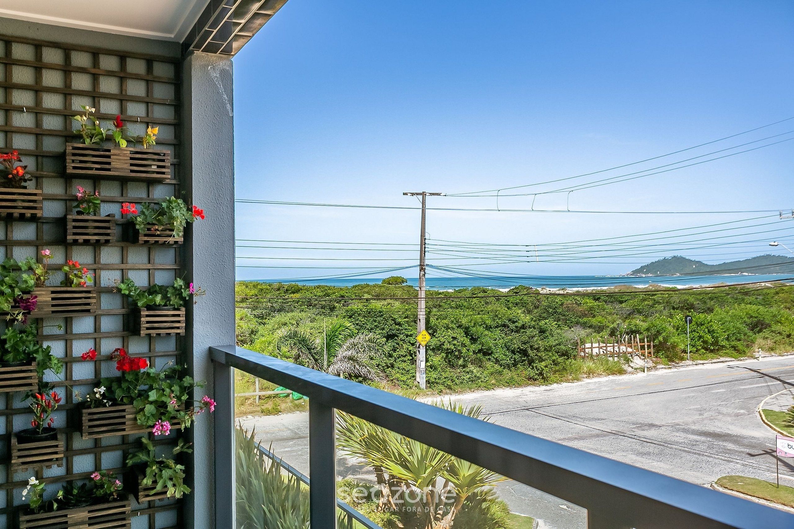 A balcony with a view of the ocean and a wooden planter with flowers.