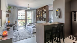 A modern hotel room with a bed, desk, and kitchenette. - Luxurious Studio Right on the Sand in Irb203 (Florianópolis)